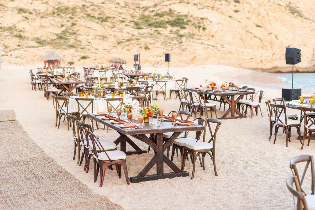 Long wooden tables set on the sand for a beachside meal